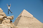 Mann, der auf einem Teil einer Pyramide in der Wüste springt; Kairo, Ägypten, Afrika
