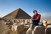 Ein Mann, der in der Nähe einer Pyramide in der Wüste sitzt
