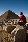 Ein Mann kauert in der Nähe einer Pyramide in der Wüste