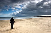 Eine Person, die alleine am Strand spazieren geht