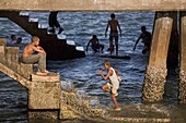 Young Boys Playing In The Sea Underneath A Jetty, Lamu, Kenya