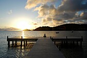 Frau sitzt am Ende eines Piers in der Abenddämmerung