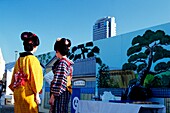 Two Geishas Dressed In Kimonos In Front Of Modern Building