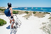 Weibliche Touristin mit Fahrrad am Strand stehend