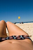 Blick durch die Beine einer am Bondi Beach liegenden Frau
