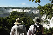 Zwei Touristen mit Hüten an den Iguacu-Fällen