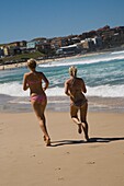 Zwei junge Frauen laufen am Bondi Beach