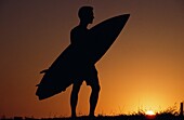 Surfer in Silhouette hält ein Surfbrett