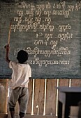 Junge zeigt auf Schrift an einer Tafel in einer Schule auf dem Land
