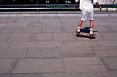 Junge fährt Skateboard auf dem Bürgersteig