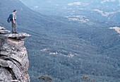 Buschwanderer in den südlichen Highlands auf einem Felsen mit Blick auf das Tal; New South Wales, Australien