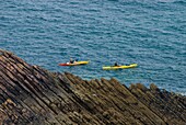 Couple Sea Kayaking Past Rocks Near Erquy