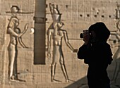 Silhouette Of Tourist Taking Pictures In Courtyard In Front Of Reliefs