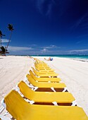 Line Of Empty Yellow Sun Loungers On The Beach