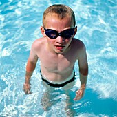 Junge mit Schwimmbrille im Schwimmbad