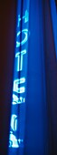 Blue Neon Sign For Hotel Seen Through Net Curtains