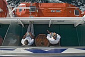 Ein Ehemann und eine Ehefrau lesen und genießen die Aussicht auf das Meer von ihrem Balkon an Bord eines Kreuzfahrtschiffes