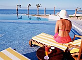 Frau auf Sonnenliege am Pool am Meer