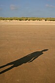 Der Schatten einer Person an einem leeren Strand