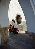 View Through Arch To Couple On A Moped.