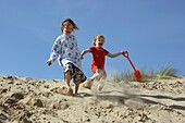 Sisters Running Down Sand Dunes Holding Hands