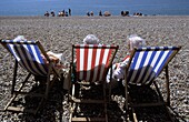 Three Old Woman On Deckchairs On Pebble Beach