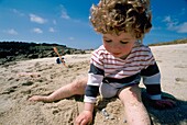 3 Year Old Girl Playing In Sand On Beach In The Scilly Isles