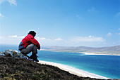 Man Looking Over Rosamol Beach With Taransay In The Distance
