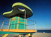 Man Sitting On Beach In The Evening In Front Of Life Guard Tower