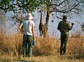 Frau und Ranger vor Giraffe auf Wandersafari durch den South Luangwa National Park