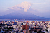 Der Berg Sakurajima bricht vor der Skyline aus