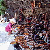 Kind betrachtet hölzerne Souvenirs, die am Strand verkauft werden