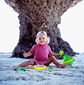 Lächelndes Mädchen, das am Strand mit Eimern und Spaten spielt