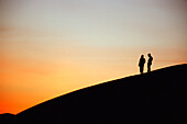 Touristen auf Sanddüne bei Sonnenuntergang, Ubari Sand Sea