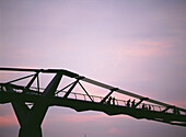 Silhouette von Menschen, die in der Abenddämmerung die Millennium Bridge überqueren