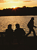 Couple On Bench With Young Woman Walking By, The Serpentine, Hyde Park