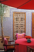 Rosa Tisch mit Schirm im marokkanischen Innenhof