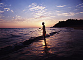 Boy Fishing At Dusk On Beach