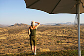 Woman Looking Over Grassland, Umbrella In Foreground