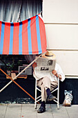 Mann liest Zeitung neben einem Gebäude