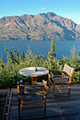 Leerer Tisch und Stühle mit Blick auf See und Berge