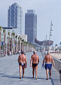 Drei Männer in Badeanzügen spazieren entlang des Olympischen Dorfes