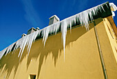 Gelbes Gebäude mit vom Dach hängenden Eiszapfen