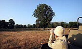 Woman In Khakis Looking Through Binoculars On Safari