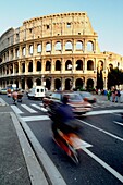 Autos und Motorroller fahren am Kolosseum vorbei, Rom