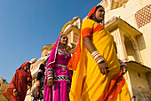 Vier Frauen in Saris gehen an altem Gebäude vorbei