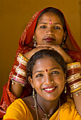 Two Women In Saris With Woman Leaning Hands On The Others Head