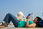 Frau liest Reiseführer vor dem Taj Mahal, Seitenansicht