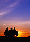 Silhouette von Zypressen neben einer kleinen Kapelle in der Abenddämmerung