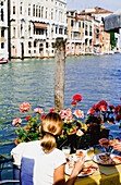 Couple Eating Meal On Edge Of Grand Canal, Rear View